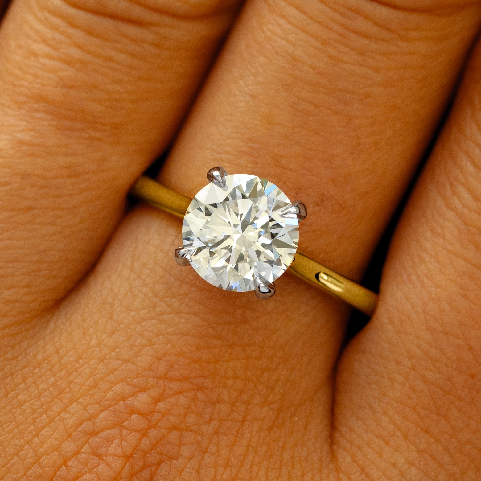 A solid 14k yellow gold and platinum Round Lab Diamond Cathedral Set Ring on a model's finger