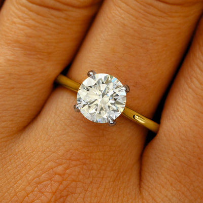A solid 14k yellow gold and platinum Round Lab Diamond Cathedral Set Ring on a model's finger