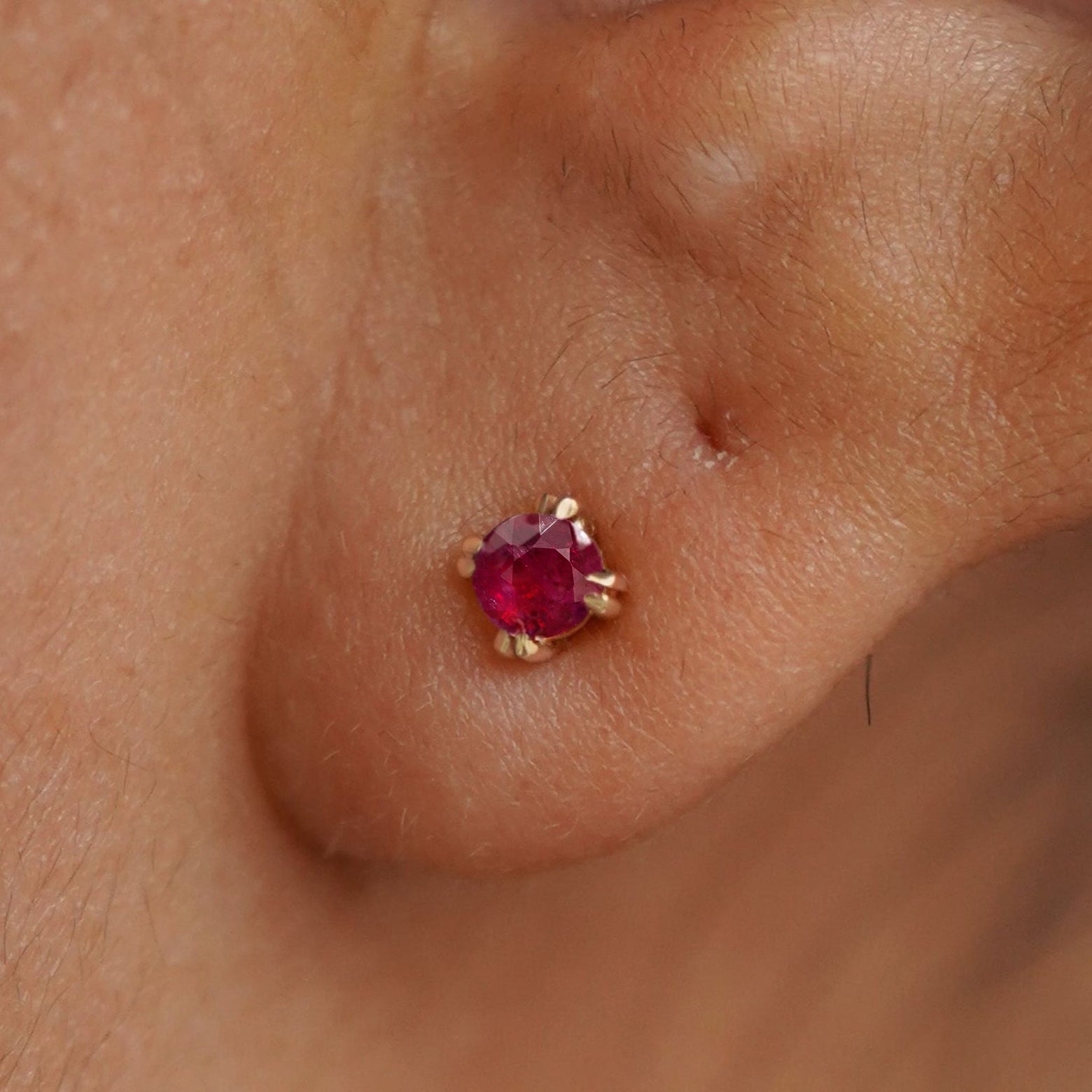 Close up view of a model's ear wearing a 14k yellow gold Ruby Earring