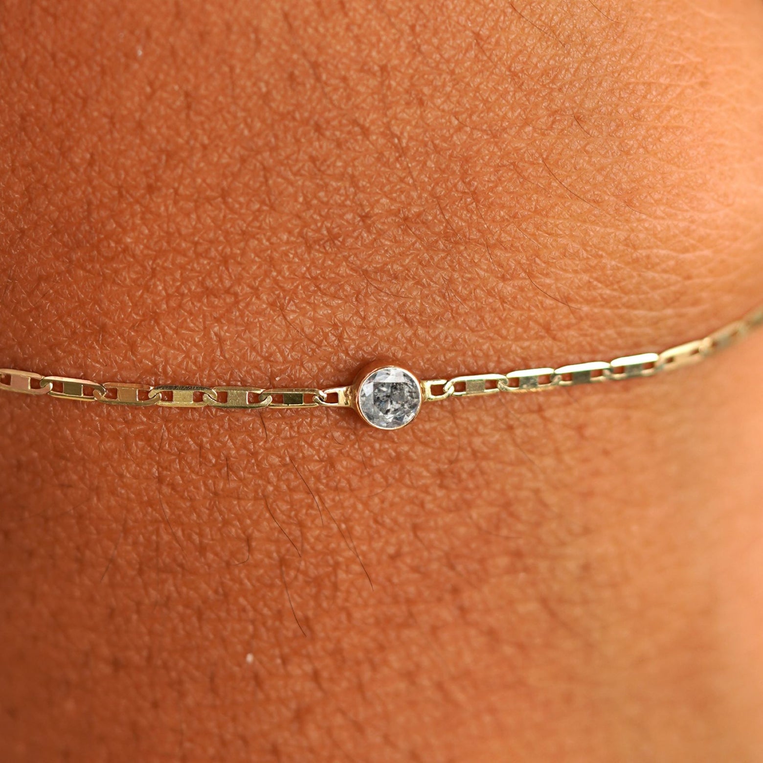 Close up view of a models wrist wearing 14k yellow gold Salt and Pepper Diamond Bracelet