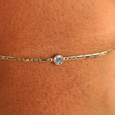 Close up view of a models wrist wearing 14k yellow gold Salt and Pepper Diamond Bracelet