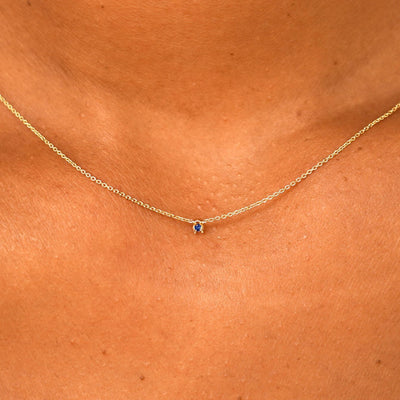 Close up view of a model's neck wearing a solid 14k yellow gold Gemstone Cable Necklace in sapphire