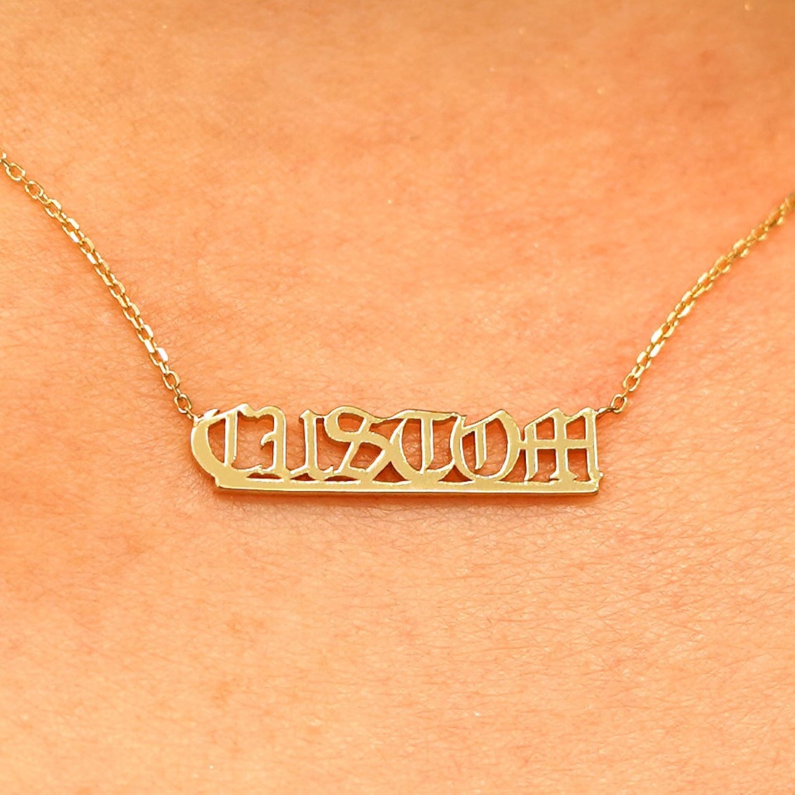 Close up view of a model's neck wearing a Small Custom Nameplate necklace that reads the word Custom