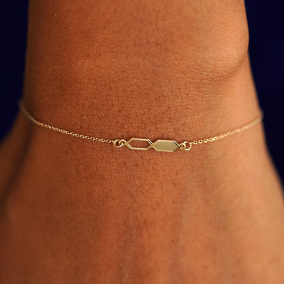 Close up view of a model's wrist wearing a solid yellow gold Tanlah Cable Bracelet