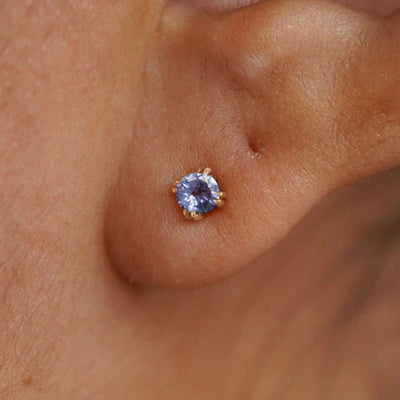 Close up view of a model's ear wearing a 14k yellow gold Tanzanite Earring