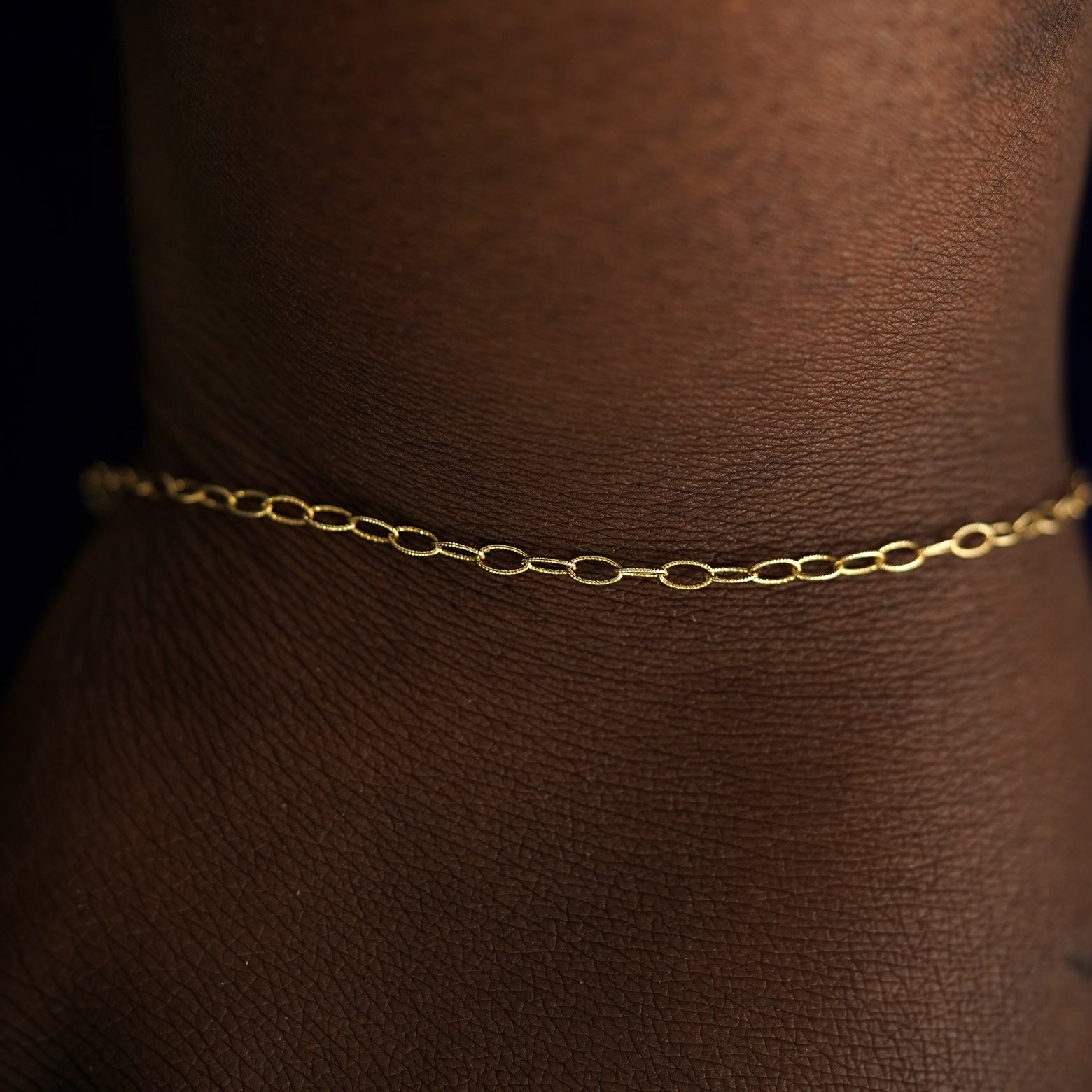 A model's wrist wearing a solid yellow gold Veren Bracelet