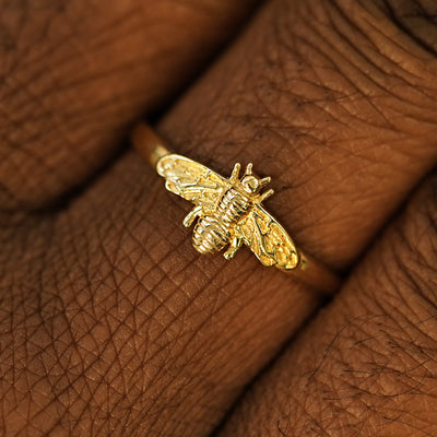 Close up view of a model's hand wearing a 14k solid gold Curvy Bee Ring