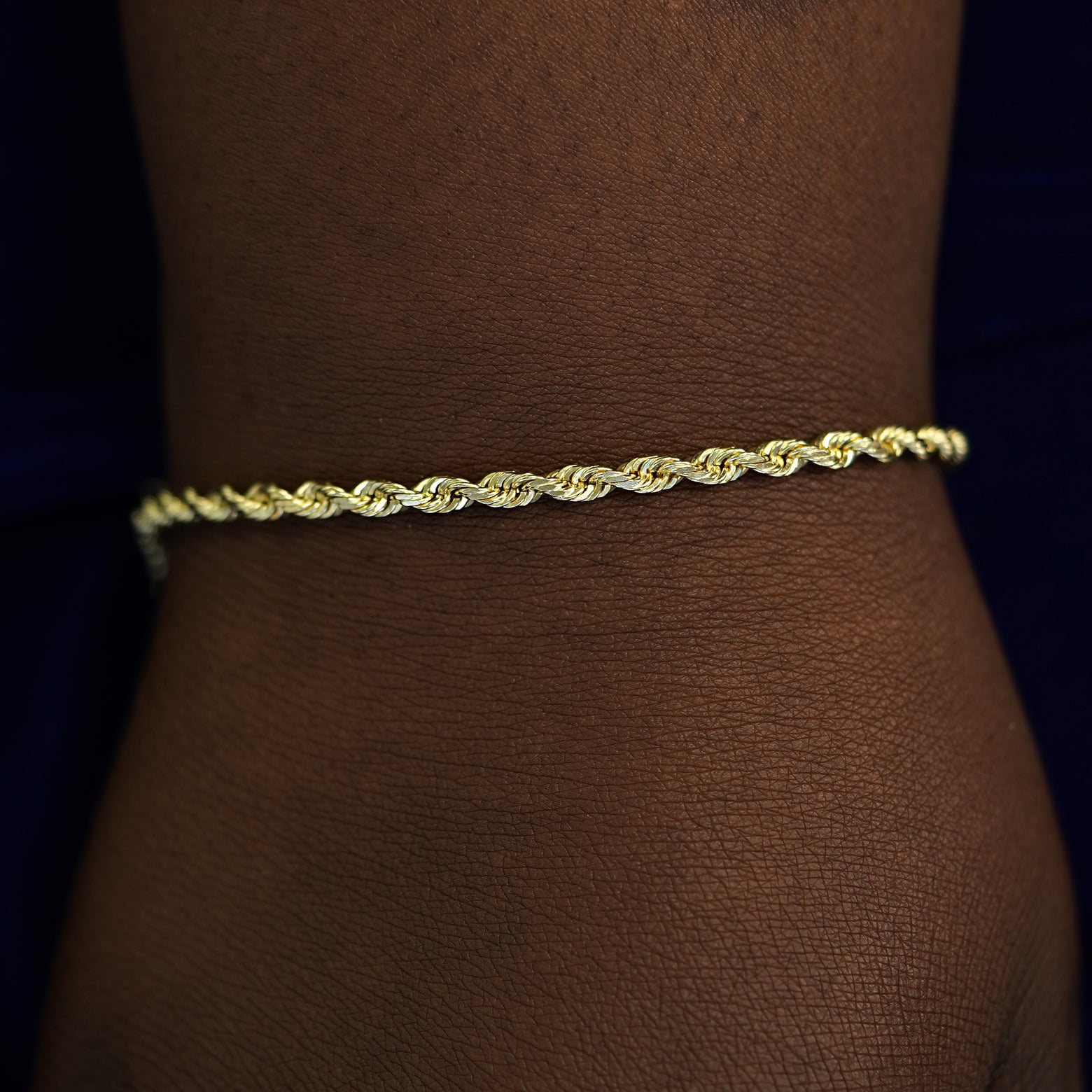 A model's wrist wearing a solid gold Thick Rope Chain Bracelet