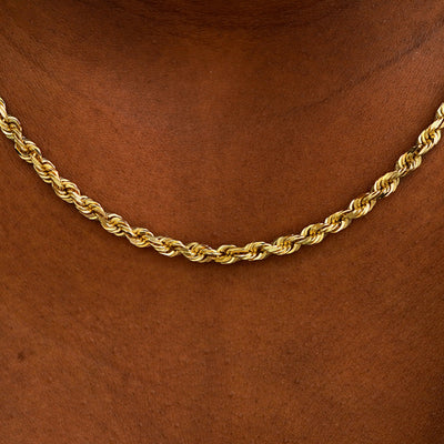 Close up view of a model's neck wearing yellow gold thick rope chain
