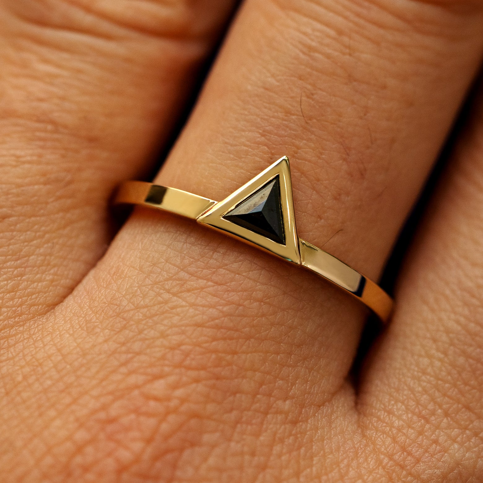 Close up view of a model's hand wearing a solid 14k yellow gold Triangle Diamond Ring