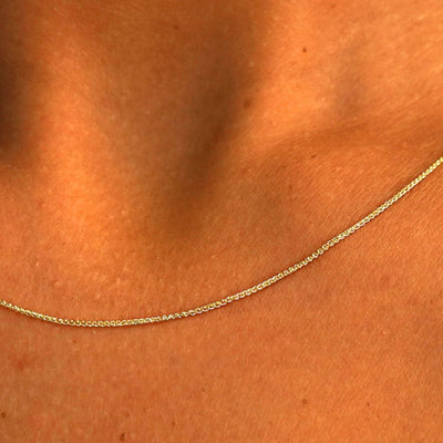Close up view of a model's neck wearing a solid 14k yellow gold Wheat Chain