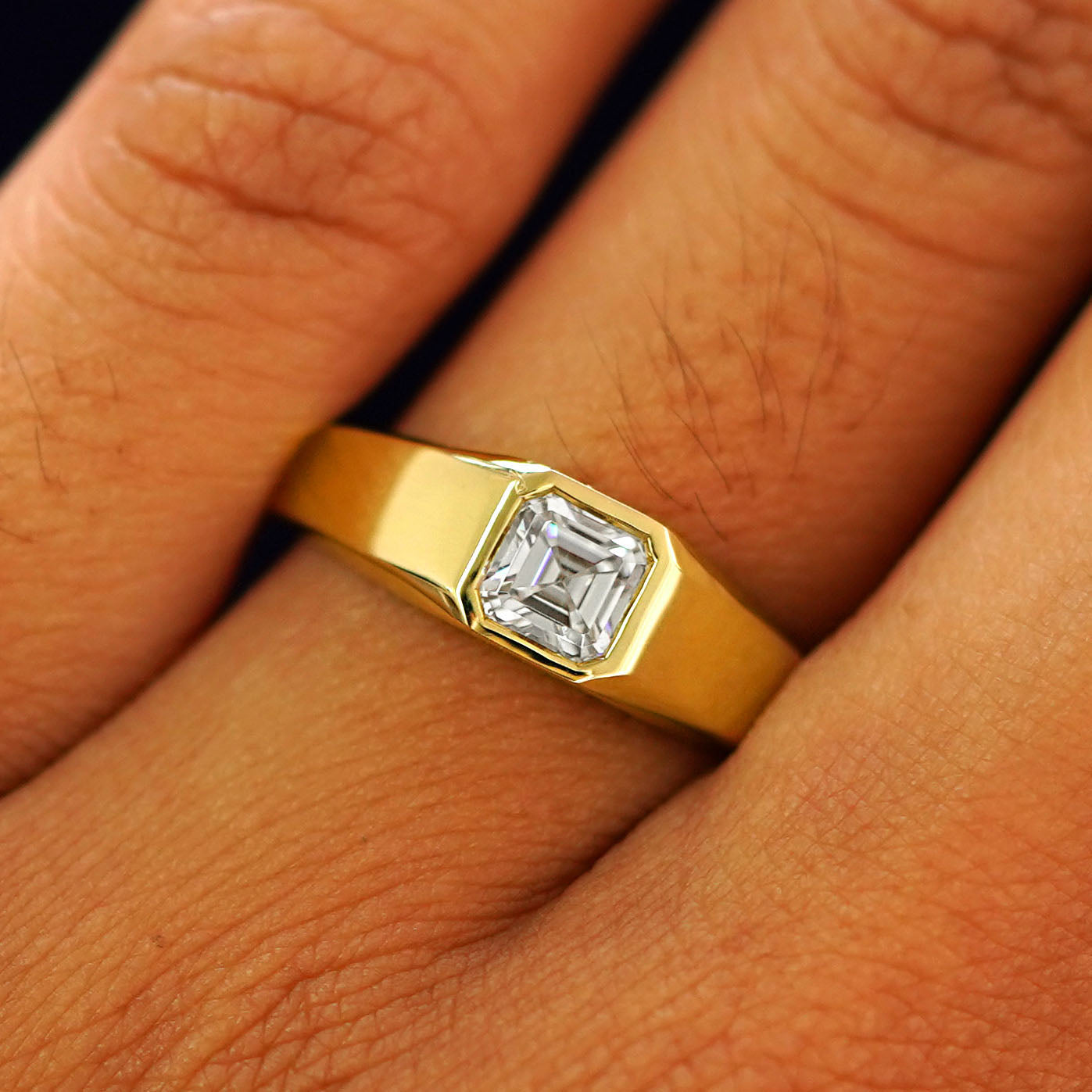 Close up view of a model's fingers wearing a yellow gold white lab moissanite Asscher Gemstone Signet Ring