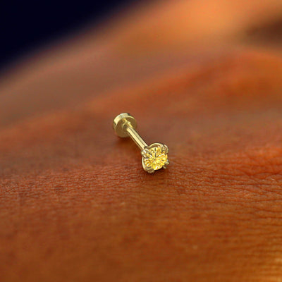 A solid 14k yellow gold Yellow Diamond Piercing resting on the back of a model's hand