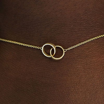 Close up view of a model's wrist wearing a solid gold Bound Together Bracelet