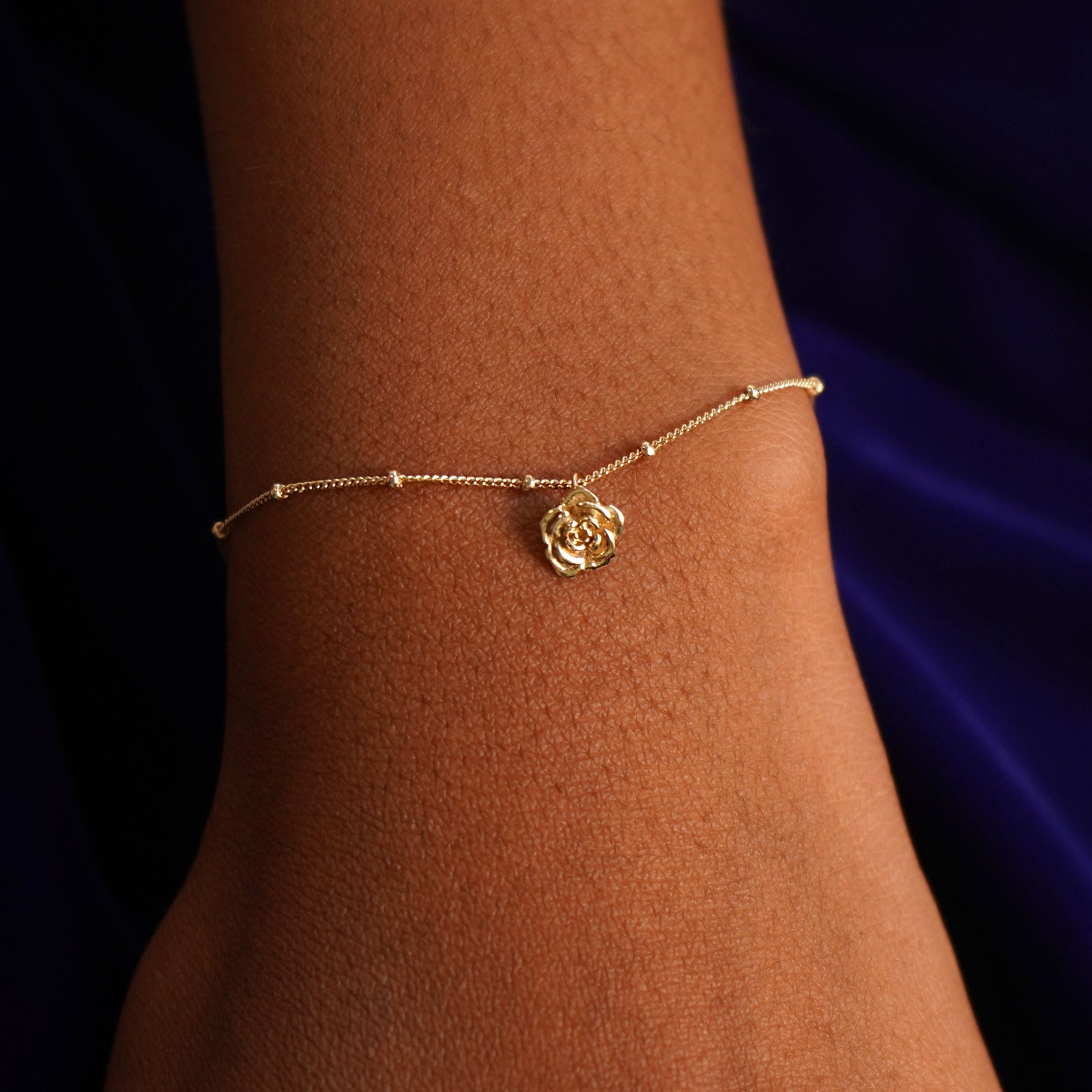 Close up view of a model's wrist wearing a yellow gold Rose Charm on a Beaded Essential Chain
