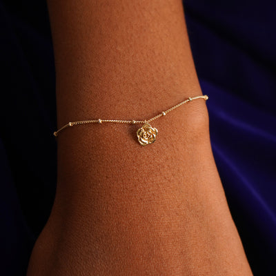 Close up view of a model's wrist wearing a yellow gold Rose Charm on a Beaded Essential Chain