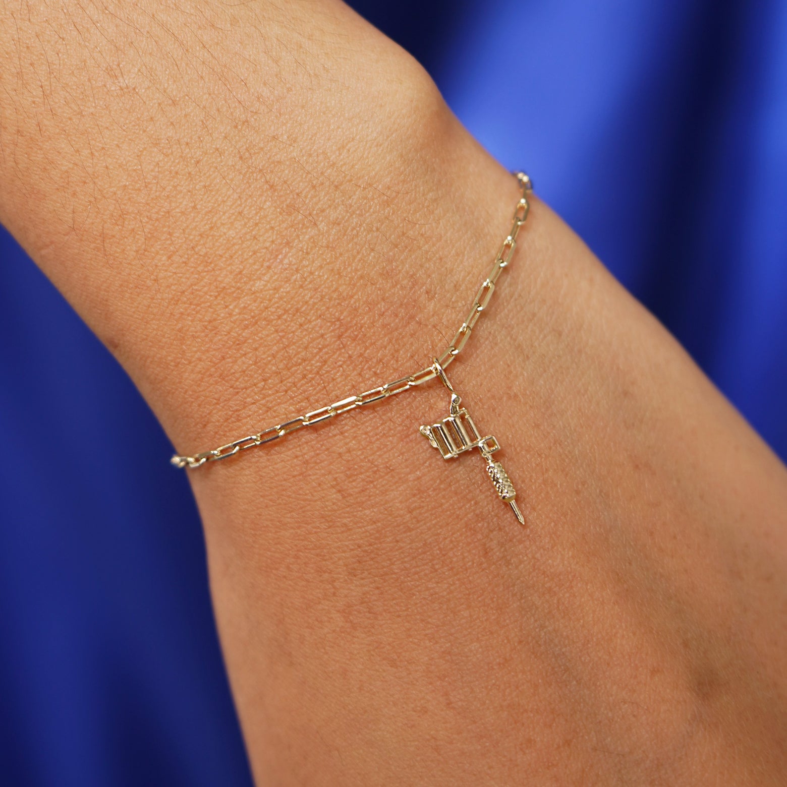 Close up view of a model's wrist wearing a yellow gold Tattoo Machine Charm on a Butch Bracelet